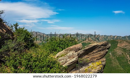A panoramic view on Daqing mountains in Inner Mongolia. Endless mountain chains. The slopes are overgrown with small bushes and grass. Desolated landscape. Clear and sunny. Bio diversity of a region Royalty-Free Stock Photo #1968022279