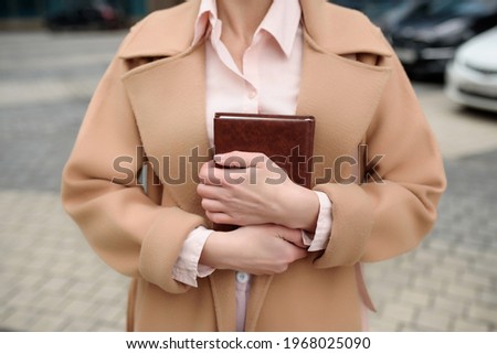 A woman holds a notebook in her hands and presses it to her, close-up