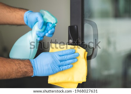 A young man cleans the handrail by spraying a cleaning agent to kill viruses for good hygiene. He put on rubber gloves and wipes. Royalty-Free Stock Photo #1968027631