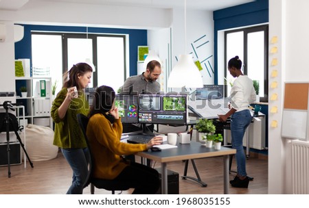 Colleagues discussing about video project adjusting film footage working in creative start up agency office with two monitors. Videographers processing movie montage with post production software