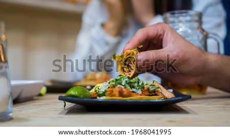 Bitten taco de pastor held by man's hands