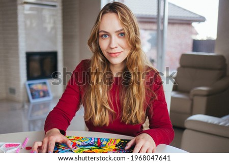 The girl draws a picture. Diamond painting. A beautiful girl with a big smile.A fashionable teenager. Beautiful girl in a white interior. Royalty-Free Stock Photo #1968047641