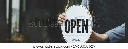 wide banner. Reopen. waitress hand turning open sign board on glass door in modern cafe coffee shop ready to service, cafe restaurant, retail store, small business owner, food and drink concept
