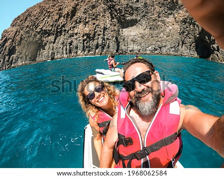 Cheerful pretty man and woman together on a jet sky having fun in summer holiday vacation - travel and happy lifestyle young people - selfie picture and smiles - blue ocean and coastline