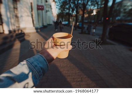 POV man holding cup with takeaway tea and lemon slice at the morning city Royalty-Free Stock Photo #1968064177