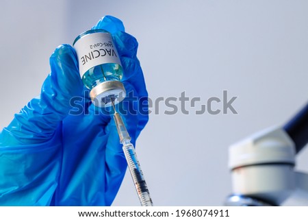Doctor hands in blue gloves holding Sars-cov-2 vaccine vial
