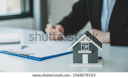 home model. Hand signing on contract after the real estate agent explains the business contract, rent, purchase, mortgage, loan, or home insurance to the buyer.