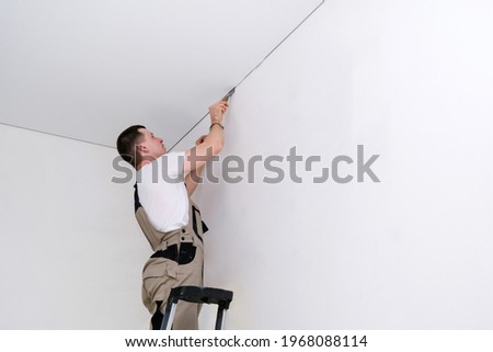 worker installs a stretch ceiling. Construction and renovation concept Royalty-Free Stock Photo #1968088114