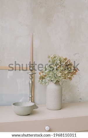 Ceramic vase with dry hydrangea, candlestick on wooden dresser. Comfortable modern interior design. Copy space.
