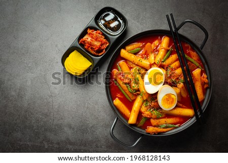Cheesy Tokbokki korean traditional food on black board background. Lunch dish. Royalty-Free Stock Photo #1968128143