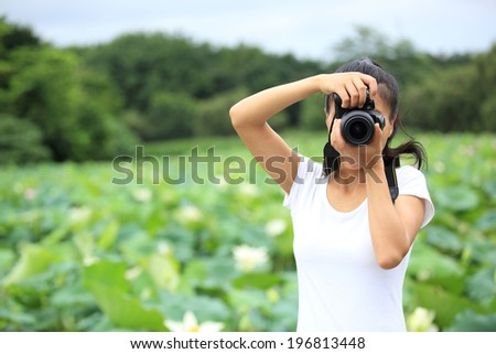 young woman photographer taking photo of blooming lotus at park