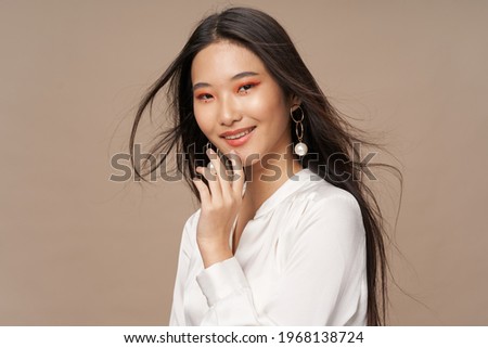 attractive asian woman in a white jacket and earrings makeup model