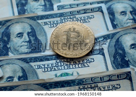 Bitcoin cryptocurrency coin lies on one hundred dollar bills