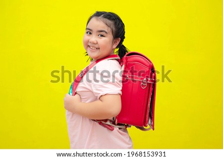 Cute female students and carrying a school bag Ice cream isolated on yellow background. Back to school concept.