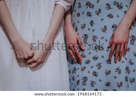 Two cropped figures of women wearing white and blue dresses. Female hands. Fashion stylish shot. Casual clothes concept