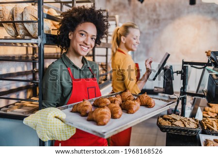 Beautiful African American and Caucasian female workers working in bakery. 
