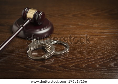 Gavel and Pair of Handcuffs on Wooden Table.