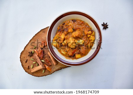 Aloo Gobi mutter is a famous Indian curry dish with potatoes and cauliflower and green peas, selective focus and wood and white back ground