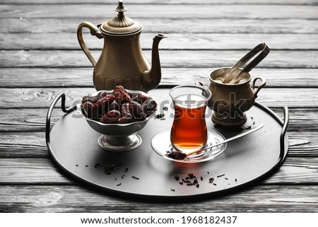 Composition with glass of tasty Turkish tea and dates on dark wooden background