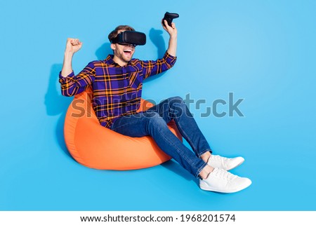 Full size profile photo of astonished funny person sit on sift chair fists up triumph isolated on blue color background