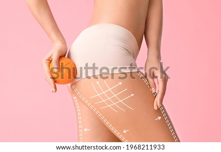 Young woman with orange fruit on color background. Concept of cellulite Royalty-Free Stock Photo #1968211933