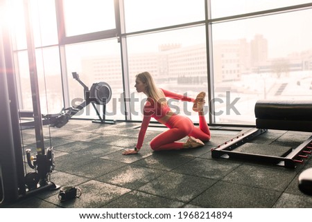 Woman practicing advanced yoga on mat against a large window