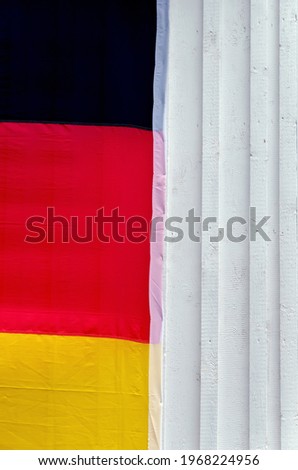 Close up of a huge German national flag on the white facade of a wooden house. Symbol. German soccer fans. Stay at home. Quarantine. Vertical. Minimalism.