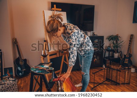 Talented female artist painting at her home.