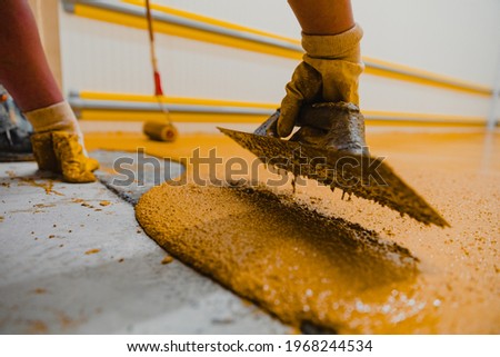Worker applying epoxy and polyurethane flooring system.These easy-to-clean products also have non-slip features. Royalty-Free Stock Photo #1968244534