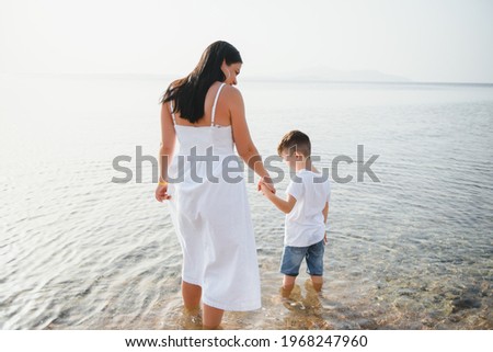 Mother and son playing on the beach at the day time. Concept of friendly family.