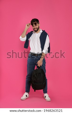 Young man with stylish backpack on pink background