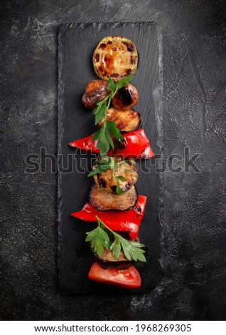 Grilled vegetables on the grill, healthy summer food on a dark background. Banner large portion of colored grilled vegetables on a dark slate. festive summer food