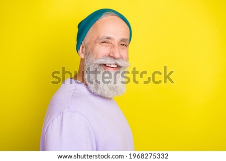 Photo of funky funny mature man dressed purple pullover headwear smiling empty space isolated yellow color background
