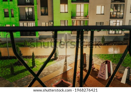 Courtyard and playground of residential area with yellow pavement at rainy weather. Bad. Patio. Architectural. Urbanisation. City. Cozy. Drainage. Wet. View from through the grates of balcony