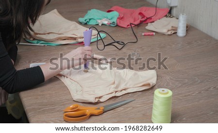 Shooting of tailor gluing pastes on woman's panties