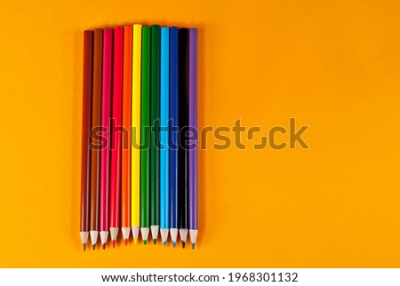 Multicolored pencils on an orange background. Copy space and free space for text on yellow background.