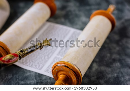 Reading a Torah scroll during a bar mitzvah ceremony with a traditional yad pointing towards the text on the parchment. Royalty-Free Stock Photo #1968302953