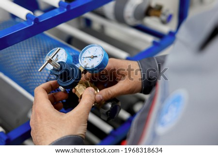 A metrology laboratory specialist takes a compressed gas cylinder for testing and verification. The man connects the pressure gauge. Analyze gas and check connections for leaks. Royalty-Free Stock Photo #1968318634
