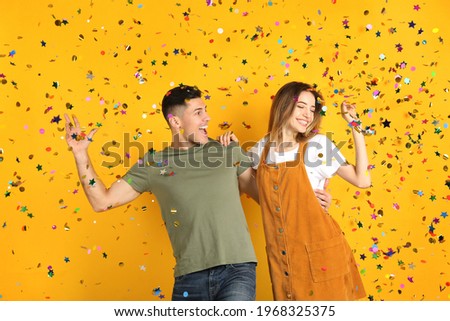 Happy couple and falling confetti on yellow background