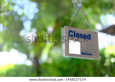 Hangs a card with information about the store closing on a shop window