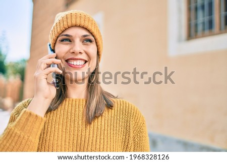 Young blonde woman smiling happy using smartphone at the city.