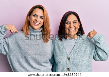 Latin mother and daughter wearing casual clothes looking confident with smile on face, pointing oneself with fingers proud and happy. 