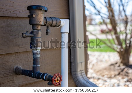Test cocks, shut off valves, and vacuum breaker to a lawn sprinkler irrigation system on the outside of a residential house Royalty-Free Stock Photo #1968360217
