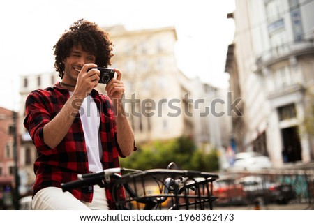 Young man traveling with camera. Handsome man traveling around the city.