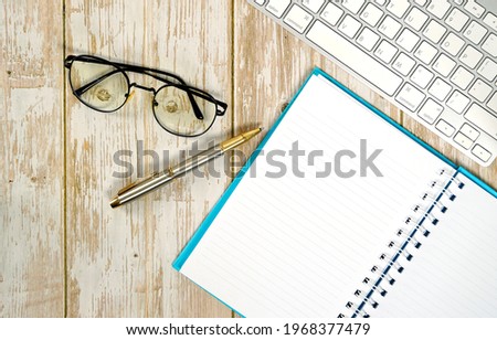 Flat lay, top view office table desk. Workspace with blank clip board, keyboard, office supplies, pens, glasses on a wooden background.