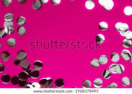 Oval frame made of silver confetti on a pink background. Monochrome image in two colors. Fashion trend concept.
