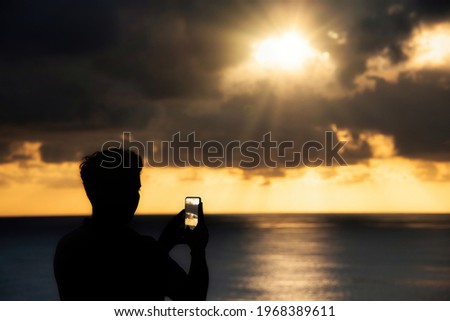 Some unrecognizable person enjoying orange sunset in North Atlantic Ocean