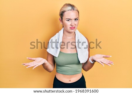 Young blonde girl wearing sportswear and towel clueless and confused with open arms, no idea concept. 