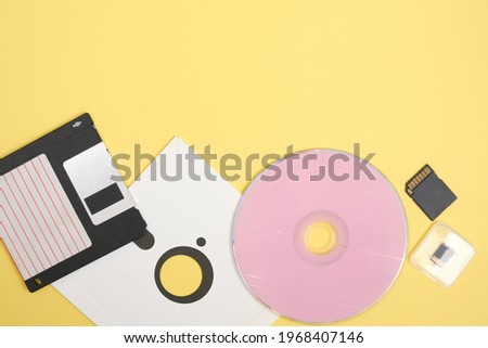 various types of disks for storing information on a yellow background, modern and retro disks and floppy disks