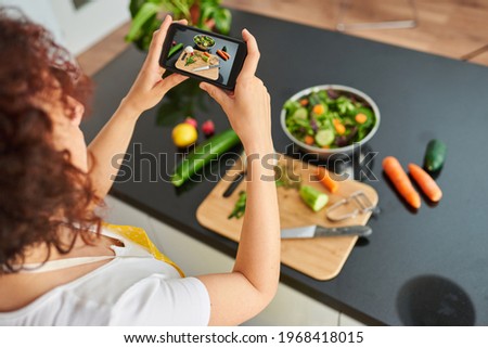 Woman taking a photo with the mobile of a salad. High quality photo.